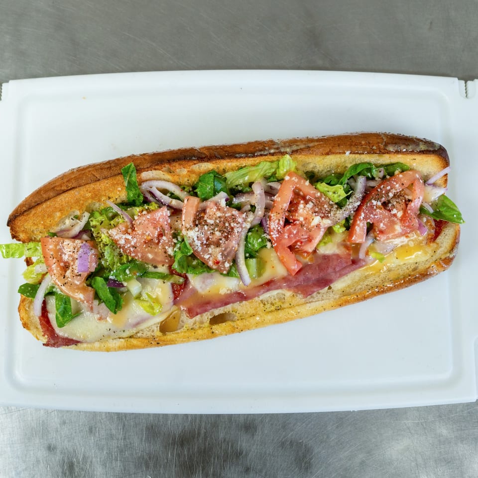Mama Ginna's Italian sub sandwich, loaded with meats, cheese, lettuce, tomatoes, and onions.