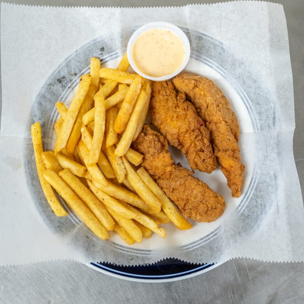 Crispy chicken tenders and golden french fries with a side of dipping sauce on a plate.