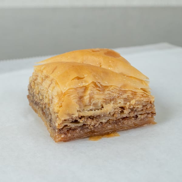 Close-up of a golden-brown baklava square with flaky layers and a nut filling.